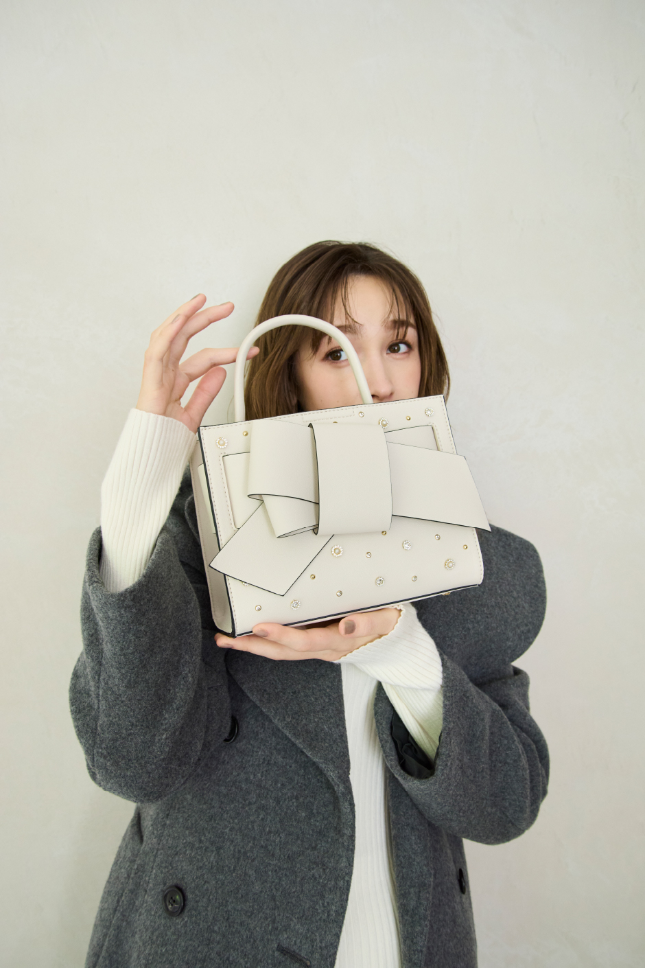 ビックカラーウールコート・ウールシルクリブニットハイネックプルオーバー・サテンランダムティアードスカート・【ルエル】ビジューパールリボンミドルバッグを着用した女性の画像