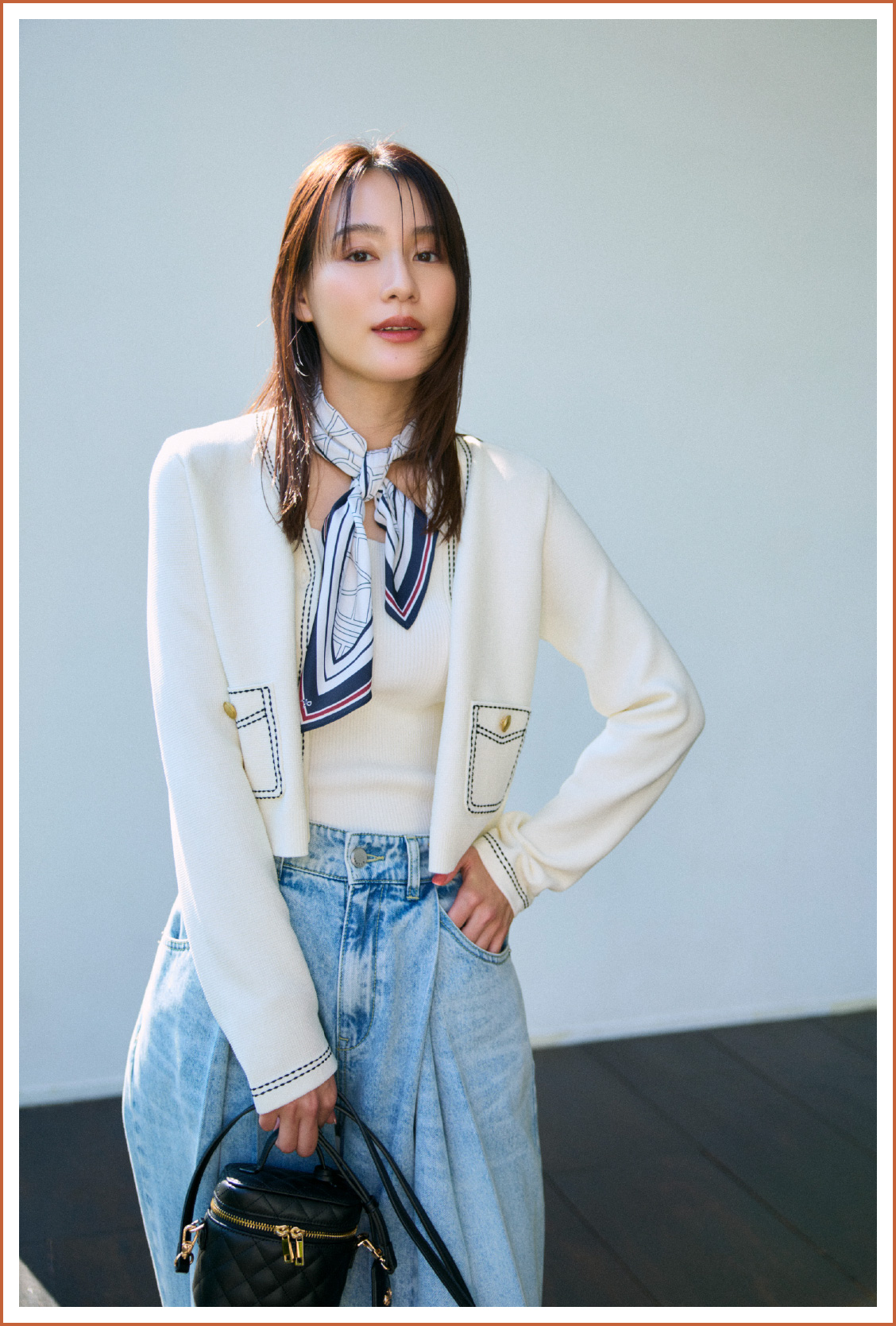 ニットカーディガン、ニットトップス、パンツ、バッグを着用した女性