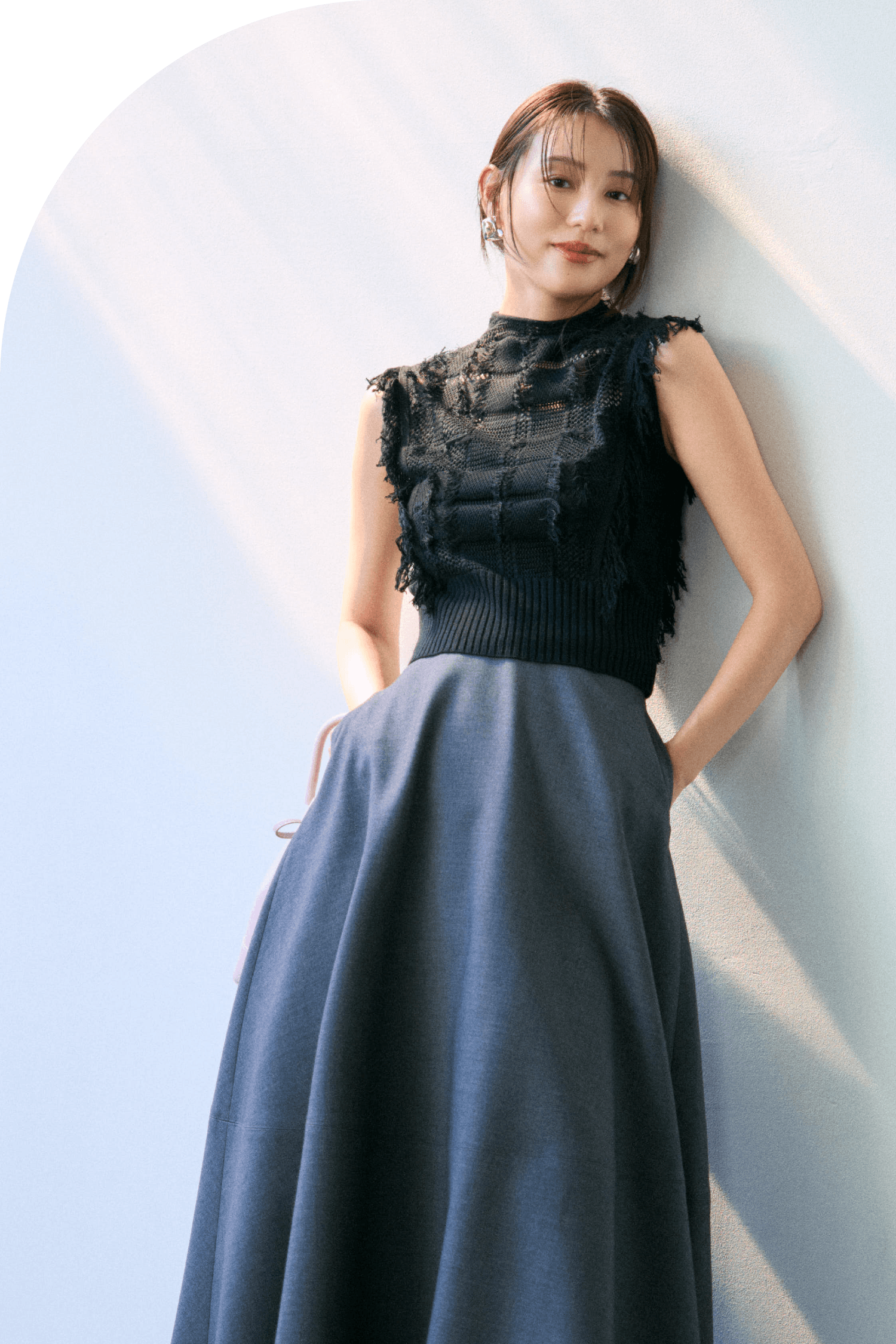 ニットトップス、スカート、イヤリング、バッグ、シューズを着用した女性