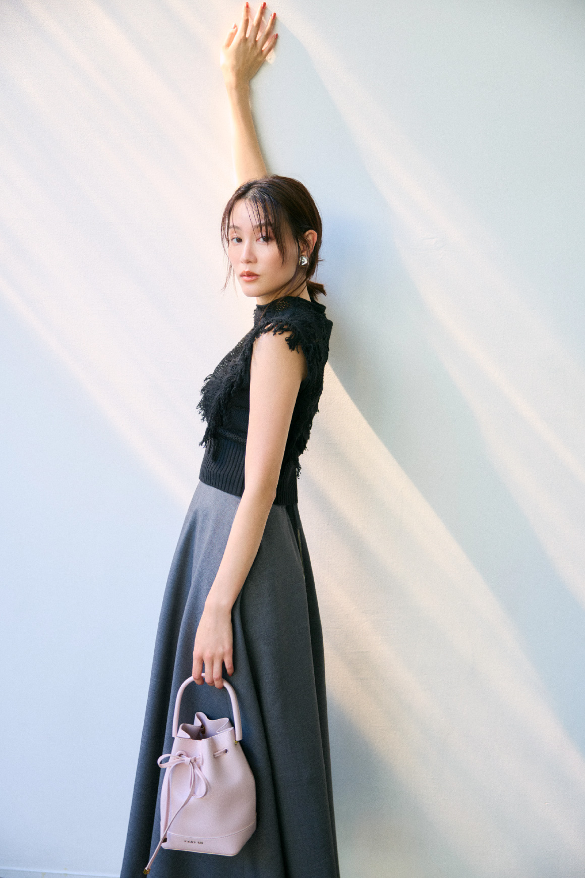 ニットトップス、スカート、イヤリング、バッグ、シューズを着用した女性