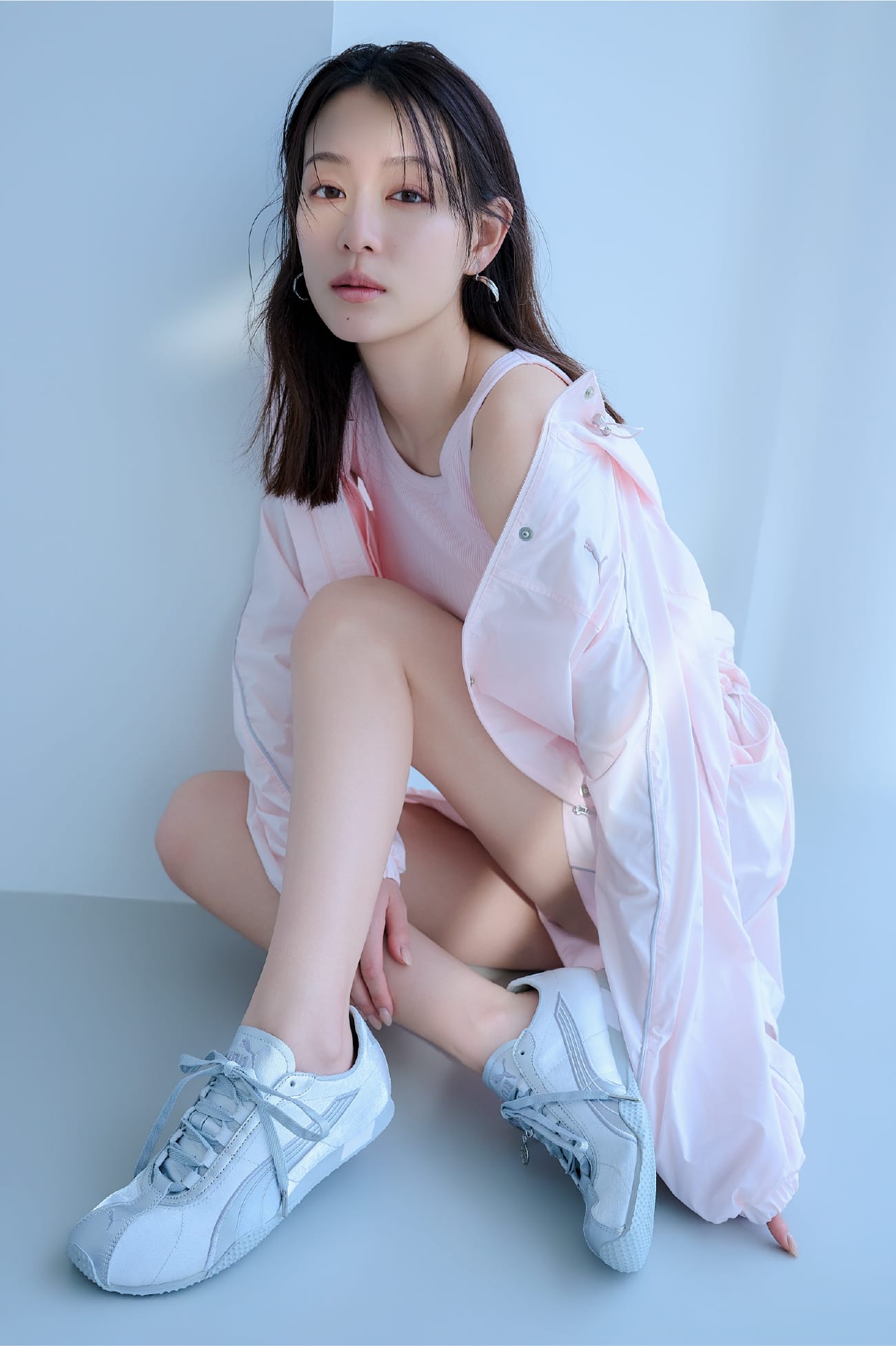 ピンクのジャケットとPUMAの白地のスニーカーを着用した女性