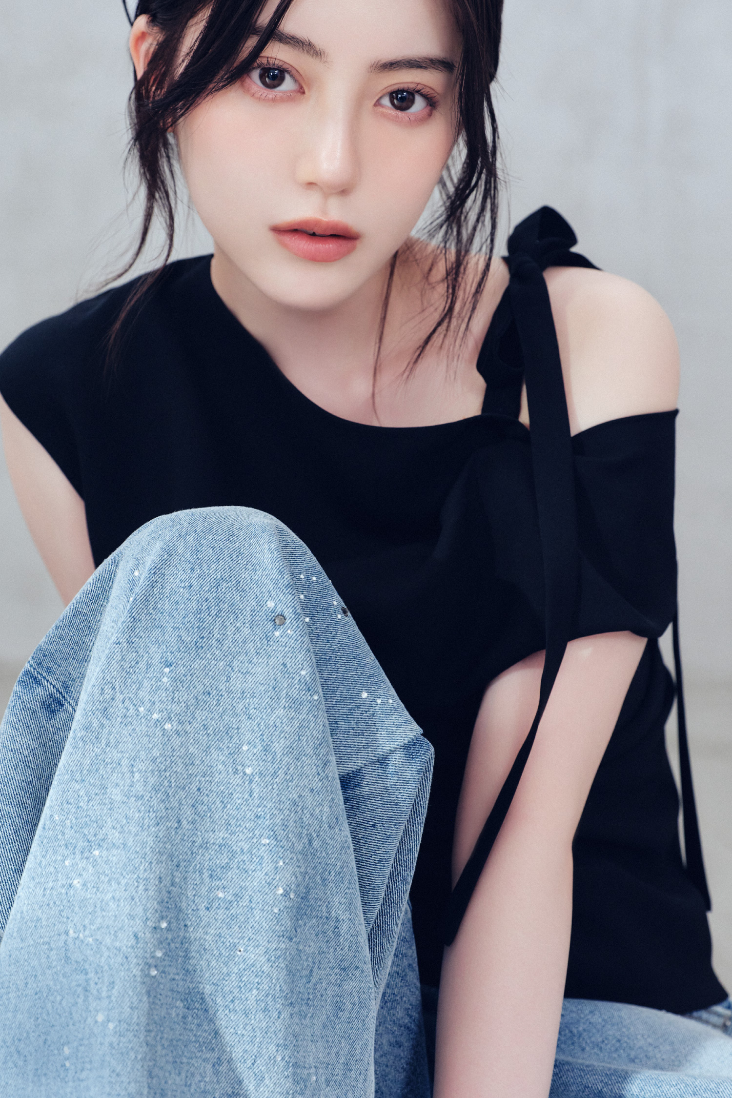 ワンサイドリボンアシメブラウス・ラインストーンセミワイドストレートデニムパンツ・シュシュクリップを着用した女性