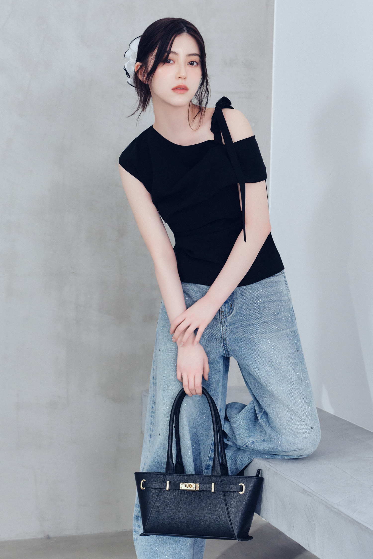 ワンサイドリボンアシメブラウス・ラインストーンセミワイドストレートデニムパンツ・シュシュクリップ・ベルトデザインレザートートバッグを着用した女性